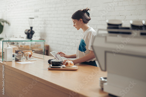 Charming young woman preparing order for customer in coffeehouse