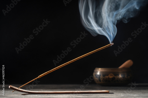 Asian incense stick in stick holder burning with smoke on black background photo