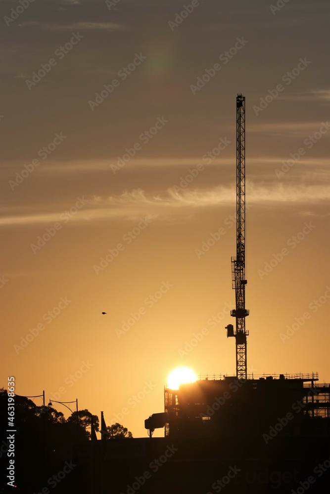 Construction crane silhouetted at sunrise.