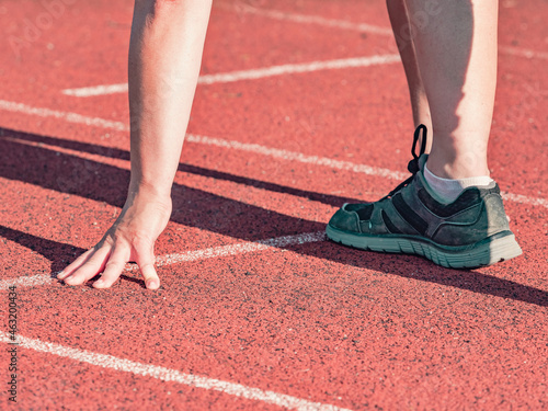 Woman on athletics track exercises in position of start