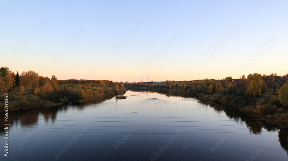 mirror river with trees along the banks against the blue sky