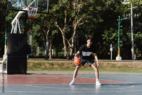 Sports and recreation concept a young male basketball player holding a basketball alone in the basketball court background © Pichsakul