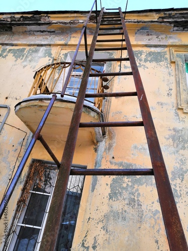  fire metal ladder leading to the roof of an old, abandoned house