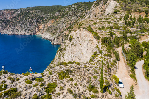 Aerial photo of man traveler on the cliff edge of beautiful and picturesque rocky coast close to Assos village on Cefalonia Ionian island, Greece