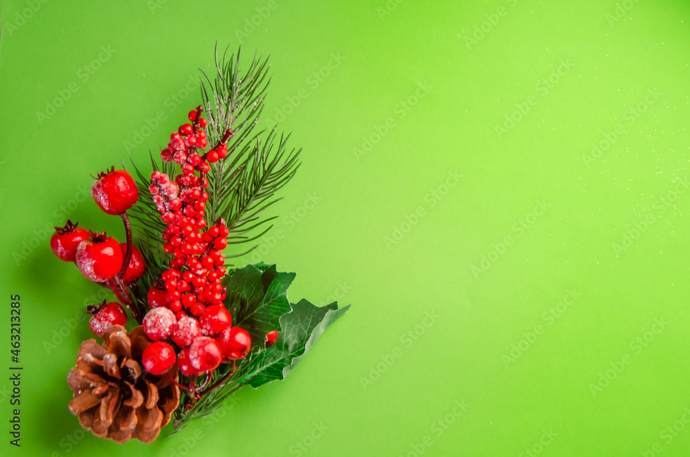 Christmas decor on a green background. A branch of a Christmas tree with decorations, red berries, cones. New Year's composition. space for text