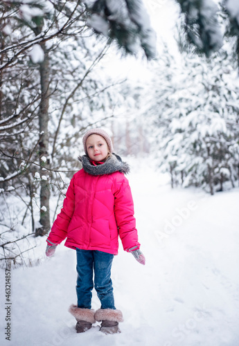 Little girl in a bright jacket plays in the winter forest © Olena Rudo