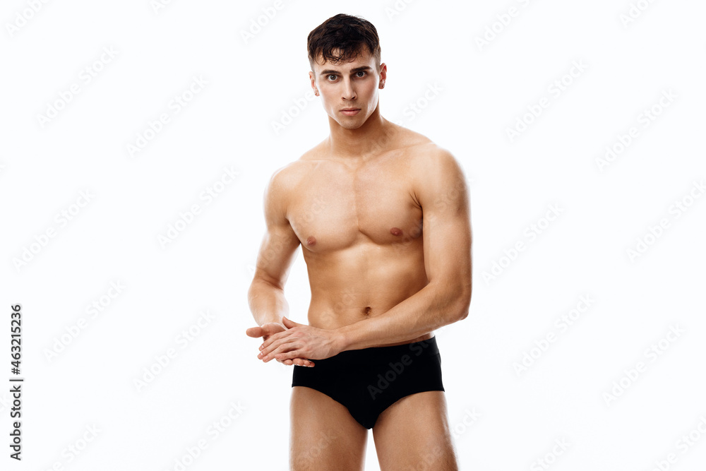 Fototapeta premium young guy athlete with a pumped-up torso gesturing with his hands on a light background cropped view