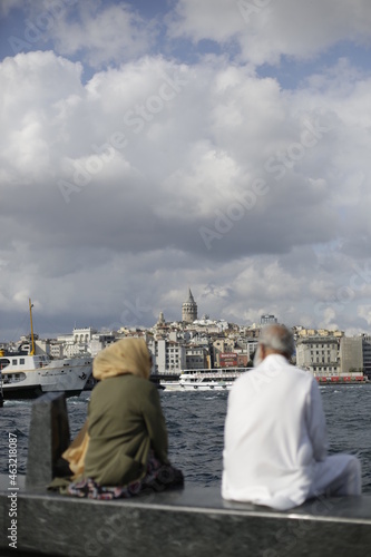A tour on the coast of the Bosphorus in Istanbul - Turkey Boats and tourists on the Galata Bridge and Galata Tower and fishermen. Seagulls are flying, an old man and his wife are back watching the sun
