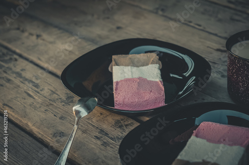 Tricolor ice cream in black plates and on a wooden table. Chocolate, strawberry and vanilla ice cream. Portions of ice cream. Selective focus