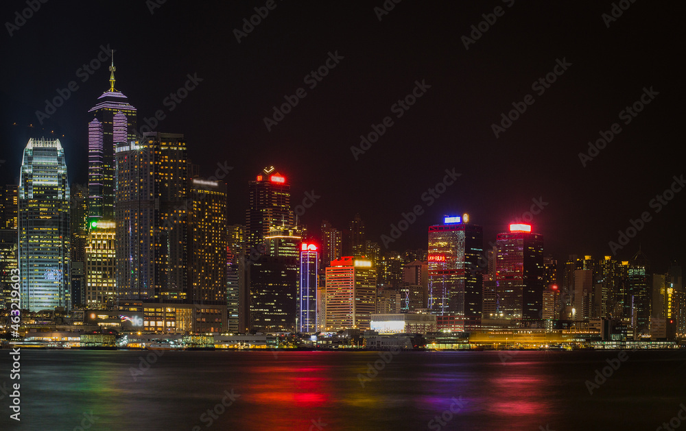 Naklejka premium Hong Kong City skyline with tourist sailboat at night. View from across Victoria Harbor HongKong.