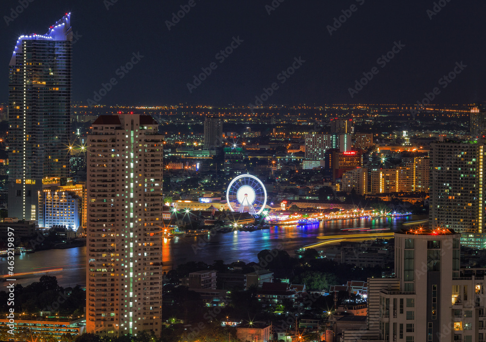 Aerial view night time lapse of landmark financial district and business center with skyscraper over Chao Phraya River at Bangkok, Thailand.