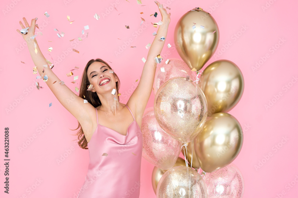 Fototapeta premium Happy young woman celebrates New Year or Happy Birthday party with air balloons throwing confetti.