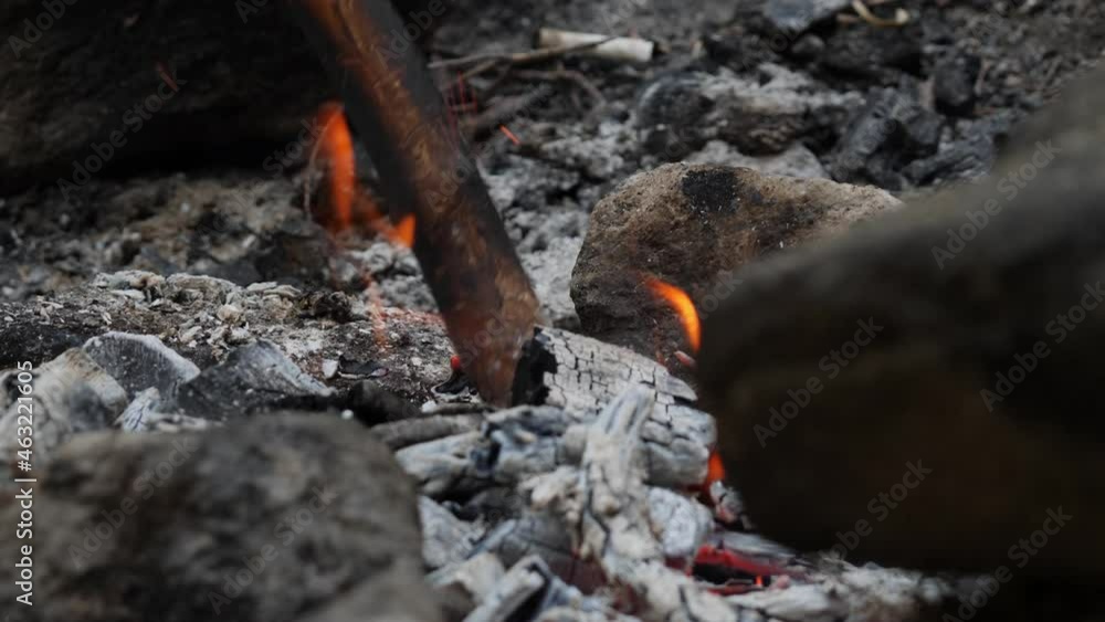 Campfire. Hearth shot in close-up. It is prepared for grilling. A stick digs up the coals and small sparks come out. The movement has slowed down. Campfire. Hearth shot in close-up. It is prepared for grilling. A stick digs up the coals and small sparks come out. The movement has slowed down.