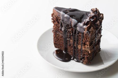 Piece of chocolate cake with chocolate dripping sauce isolated on white with text space photo