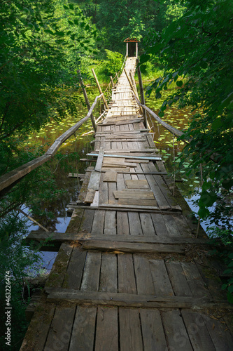 Fototapeta Naklejka Na Ścianę i Meble -  Suspended wooden bridge over a small river in a summer forest