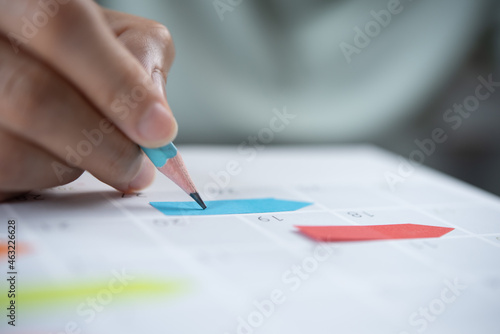 Close-up of business woman taking note on 2022 calendar desk, making agenda on office table. Event planner timetable. Calendar event plan