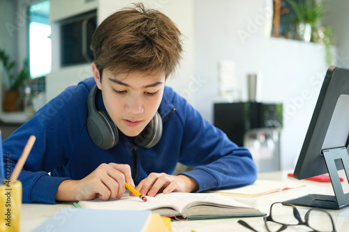 Student boy with tablet computer learning at home.