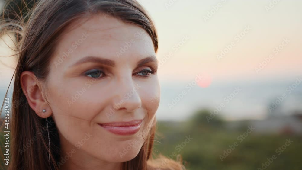 Close up portrait of stunning young woman with long brown hair and blue eyes posing on ocean beach. Sporty female relaxation during evening training on fresh air. Close up portrait of stunning young woman with long brown hair and blue eyes posing on ocean beach. Sporty female relaxation during evening training on fresh air.