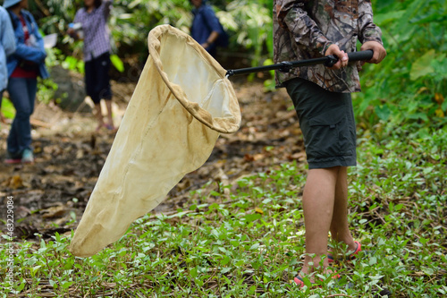 person holding a swift net for catch insect speciment in the field. photo