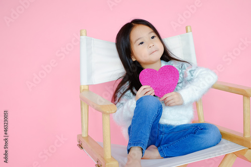 Portrait beautiful cute asian child girl on pink background with red heart sign, valentine day in love concept
