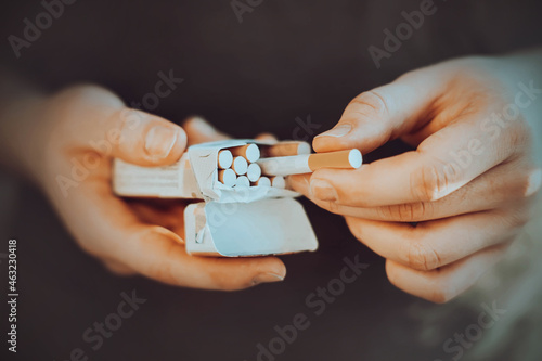 A man holds an open pack of cigarettes in his hands and takes a cigarette out of it to light it. Nicotine addiction. The habit of smoking.