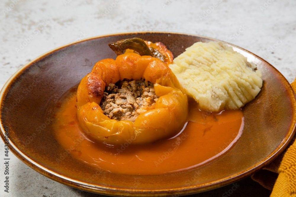 yellow stuffed pepper with mashed potatoes on the side served on a plate 