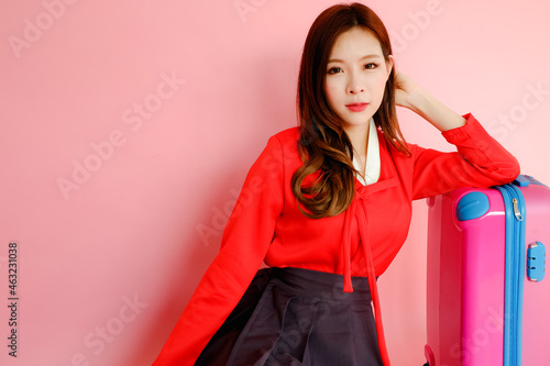 Portrait beautiful asian woman wearing red modern hanbok dress korea style on pink background with traveling luggage bag, travel korea concept