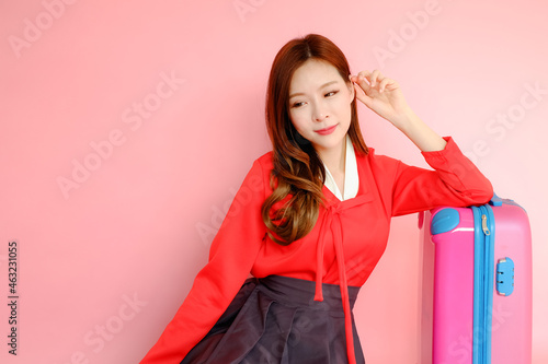 Portrait beautiful asian woman wearing red modern hanbok dress korea style on pink background with traveling luggage bag, travel korea concept