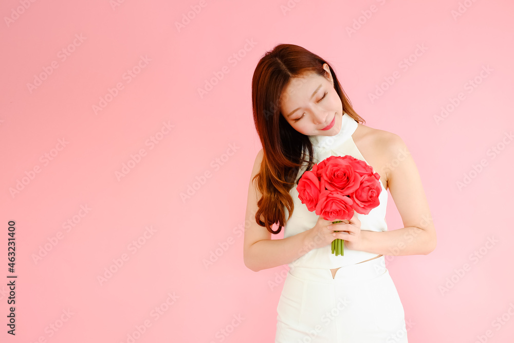 Portrait beautiful asian woman on pink background with red flower bouquet holding in hand, happy valentine day in love concept Portrait beautiful asian woman on pink background with red flower bouquet holding in hand, happy valentine day in love concept