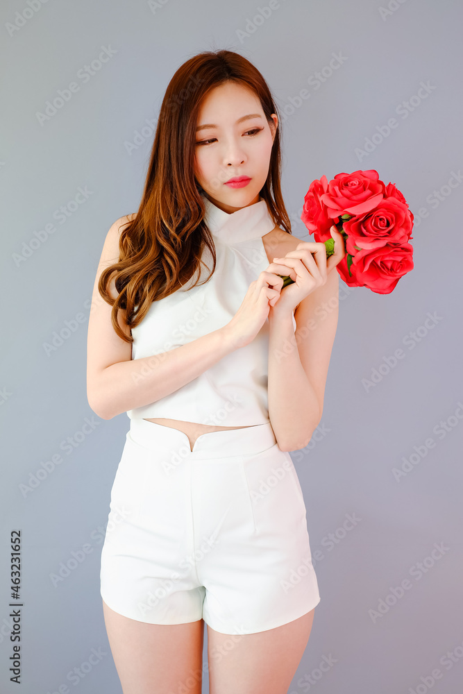 Portrait beautiful asian woman on gray background with red flower bouquet holding in hand, happy valentine day in love concept Portrait beautiful asian woman on gray background with red flower bouquet holding in hand, happy valentine day in love concept