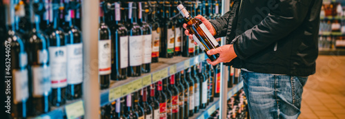 Fotografie man hand holding bottle wine in grocery store in supermarket