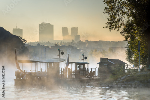 Amazing foggy view of small ferry boat in Prague. Pankrac district in the background.