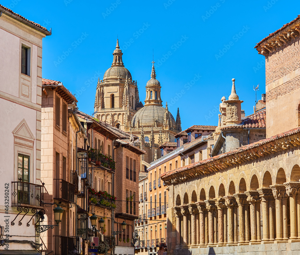 Domes of the Cathedral of Segovia with the Juan Bravo street and the atrium of the Romanesque church of San Martin in the foreground. View from Medina del Campo square. Segovia, Spain.