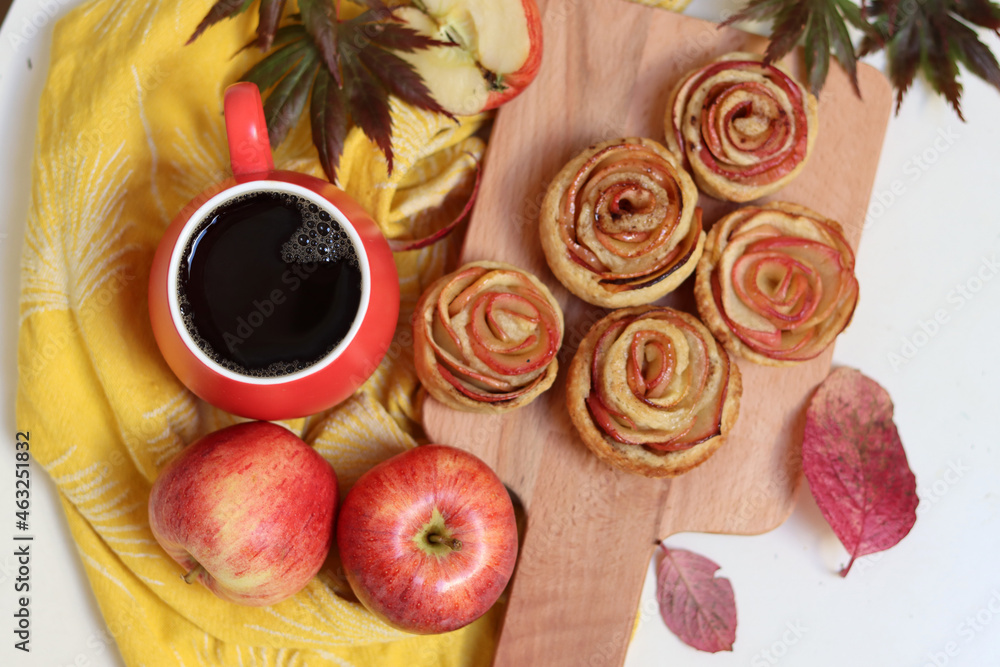 Cup of black tea and apple cupcakes. Close up photo of beautiful dessert tart. Rose shaped Apple Pies on a table. 