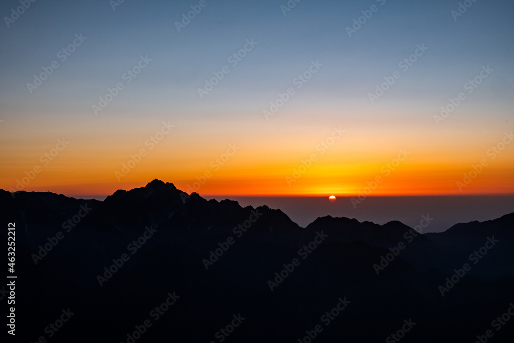 山のシルエットと夕日