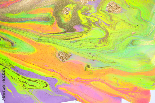 Mixture of acrylic bright paints with yellow gold glitter. Marble imitation background.