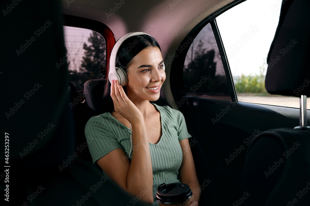 Young woman listening to music in modern taxi