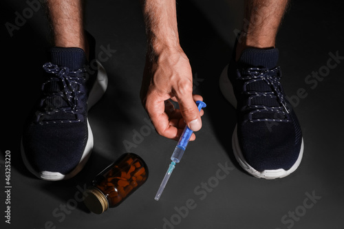 Man taking syringe from black floor, closeup. Doping concept