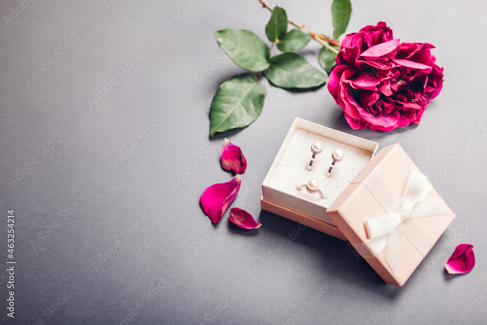 Pearl earrings and ring in gift box with rose on grey background. Stylish accessories as present for Valentine's day Pearl earrings and ring in gift box with rose on grey background. Stylish accessories as present for Valentine's day