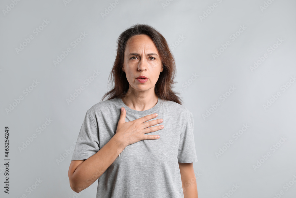 Mature woman suffering from breathing problem on light background Mature woman suffering from breathing problem on light background