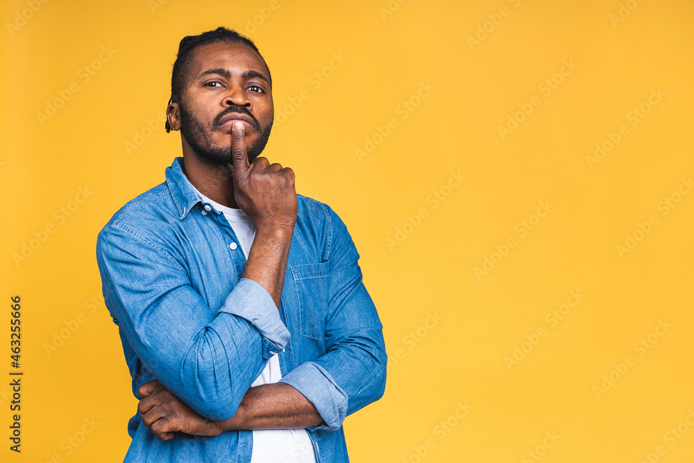 Thinking black African American man with serious expression looking, posing isolated over yellow background. Thinking black African American man with serious expression looking, posing isolated over yellow background.