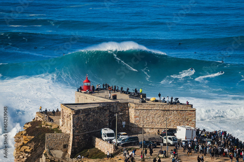 Surfer riding huge wave near the Fort of Sao Miguel Arcanjo Lighthouse in Nazare, Portugal. Nazare is famously known for having the biggest waves in the world. photo