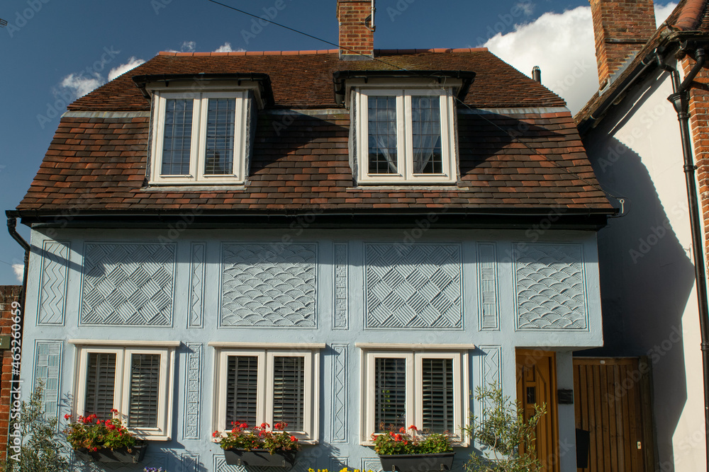 Facade of blue house with roof extension and decorations on wall at Saffron Walden, England
