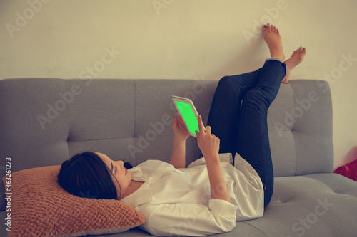 girl lying on the sofa playing mobile phone
