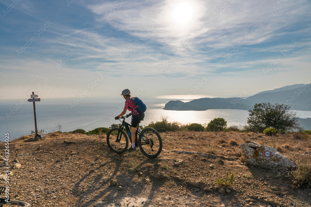 nice active woman riding her electric mountain bike in the abandoned Iron Ore mines of Calamite peninsula on the Island of Elba, Tuscan Archipelago, Tuscany,Italy 
