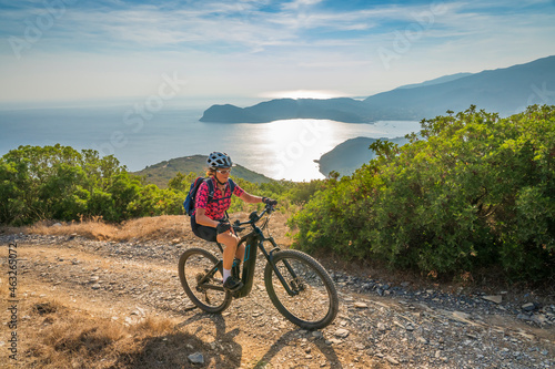 nice woman riding her electric mountain bike at the coastline of mediterranean sea on the Island of Elba in the tuscan Archipelago Tuscany, Italy