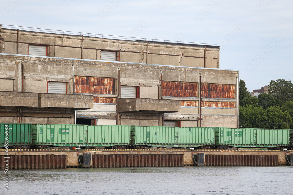 Old brick building with train tracks and cargo train standing nearby. Cargot rain in green color. Old brick building with train tracks and cargo train standing nearby. Cargot rain in green color.