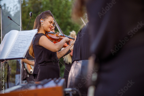 Charming female violinist playing in orchestra on the street