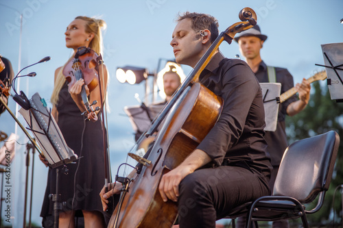 Male cellist playing in orchestra at outdoor concert photo