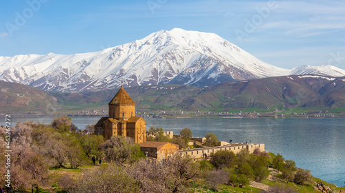 ‘Armenian Holy Cross Cathedral’ surrounded by tree in blossom, in a middle of ‘Akdamar Island’ Akdamar Adasi, Lake Van, Turkey. 